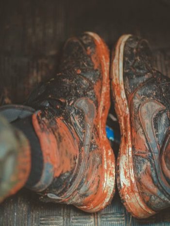 Close-up of muddy boots inside a vehicle, capturing the essence of adventure and rugged outdoor lifestyle.