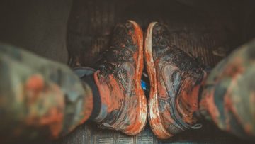 Close-up of muddy boots inside a vehicle, capturing the essence of adventure and rugged outdoor lifestyle.
