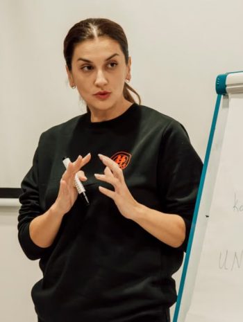 Woman confidently presenting with a flip chart in a classroom setting.
